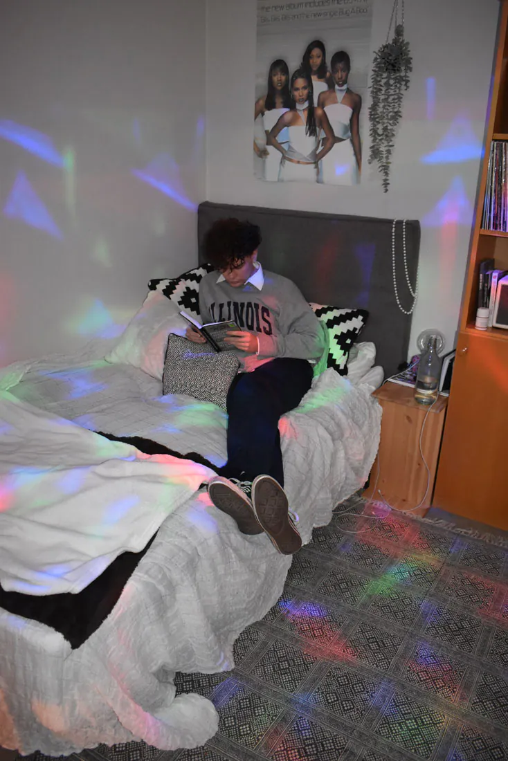Student läser bok i sängen i internatrum